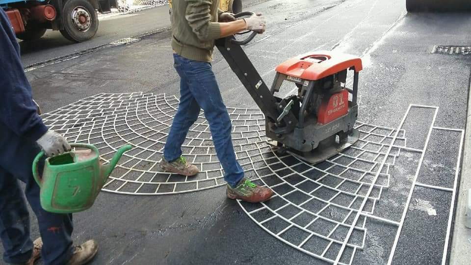 Restyling di via Zavattari: operai al lavoro per posare l’asfalto “stampato”