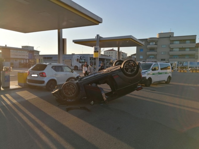 Finisce contro un’auto ferma a fare benzina e si ribalta